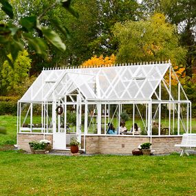 Umweltaufnahme mit dem Victoria-Gewächshaus, mit Menschen drinnen und Herbstgarten draußen